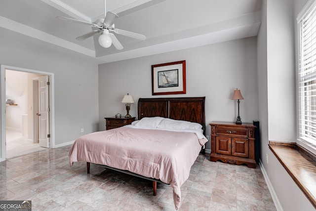 bedroom featuring a tray ceiling, ceiling fan, and ensuite bathroom