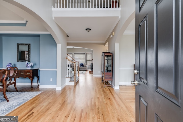 foyer with crown molding, light hardwood / wood-style flooring, and a high ceiling