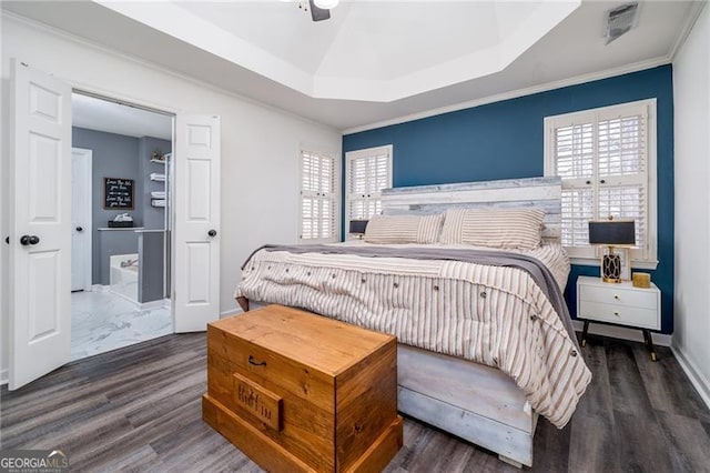 bedroom featuring dark wood-type flooring, ceiling fan, ornamental molding, and a raised ceiling