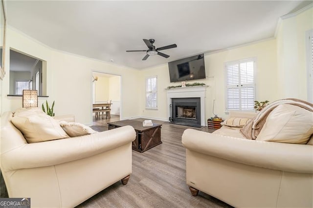 living room featuring ornamental molding, light hardwood / wood-style floors, and ceiling fan