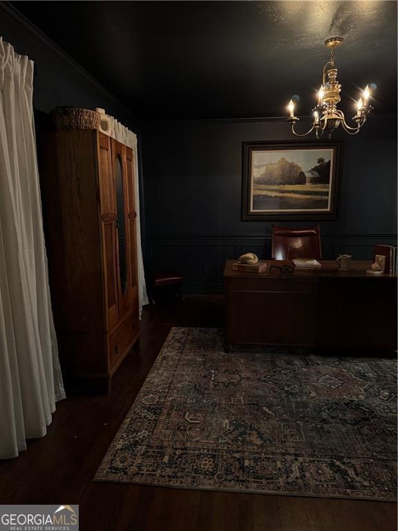 interior space with a chandelier, wainscoting, dark wood-type flooring, and ornamental molding