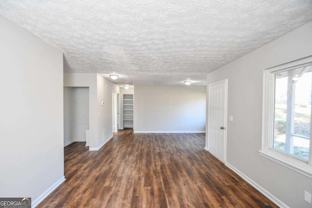 empty room with dark wood-type flooring and a textured ceiling