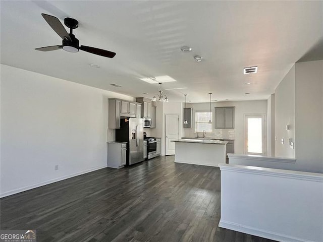 unfurnished living room featuring dark wood-type flooring and ceiling fan