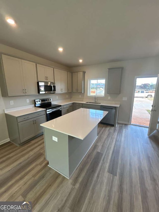 kitchen featuring dark wood-type flooring, sink, gray cabinetry, a center island, and stainless steel appliances