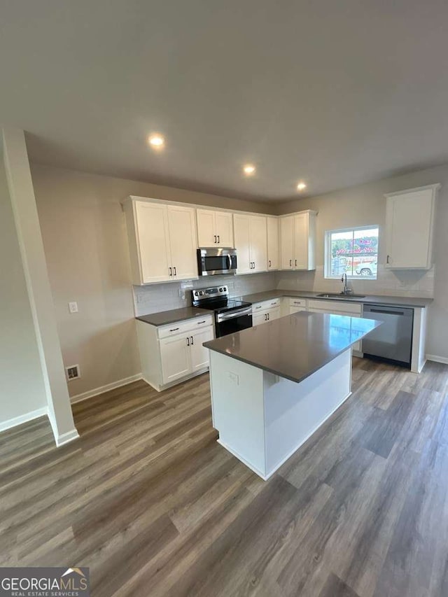 kitchen featuring sink, a center island, dark hardwood / wood-style flooring, stainless steel appliances, and white cabinets