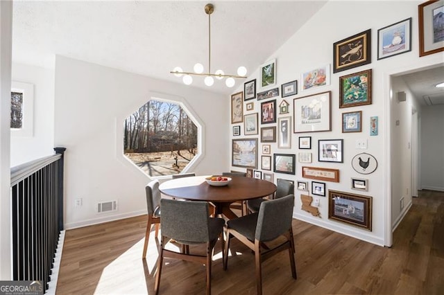 dining space with dark hardwood / wood-style flooring, lofted ceiling, and a chandelier