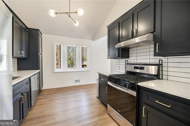 kitchen with lofted ceiling, stainless steel appliances, decorative backsplash, decorative light fixtures, and light wood-type flooring