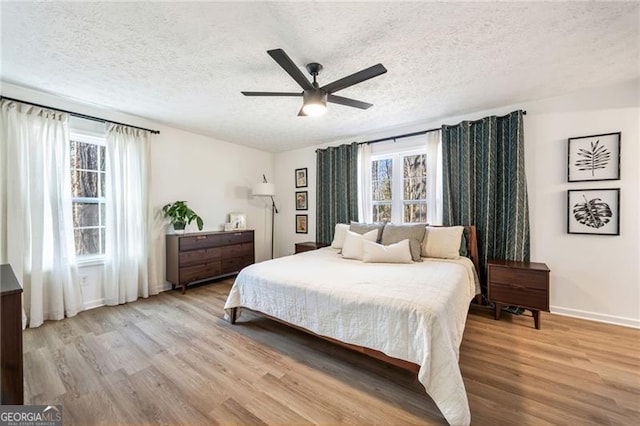 bedroom with a textured ceiling, multiple windows, and light wood-type flooring