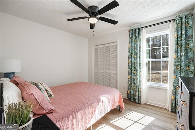 bedroom featuring multiple windows, a closet, a textured ceiling, and light hardwood / wood-style flooring