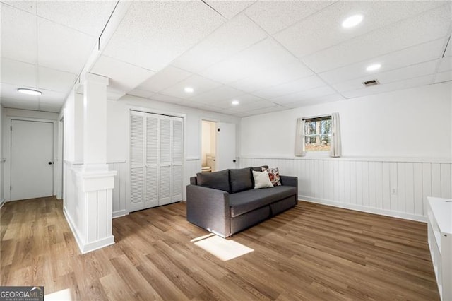 living room featuring a paneled ceiling and light hardwood / wood-style flooring