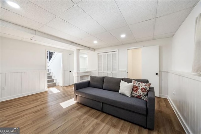 living room with a paneled ceiling, hardwood / wood-style floors, and decorative columns