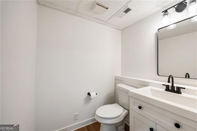 bathroom featuring hardwood / wood-style flooring, vanity, a paneled ceiling, and toilet