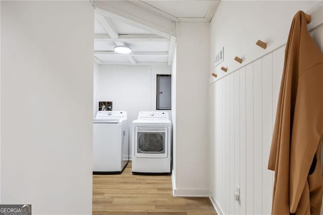 washroom featuring washing machine and clothes dryer, light hardwood / wood-style floors, and electric panel