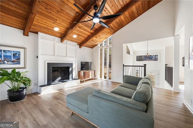 living room featuring high vaulted ceiling, a fireplace, beamed ceiling, wooden ceiling, and light wood-type flooring