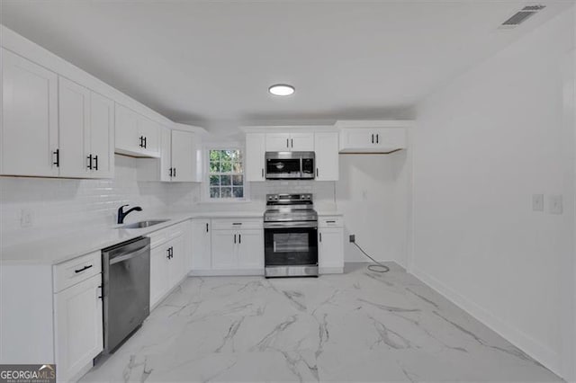 kitchen with stainless steel appliances, white cabinetry, sink, and tasteful backsplash