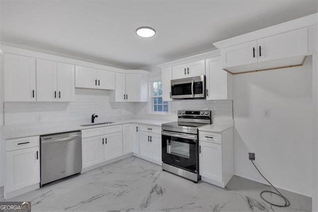 kitchen featuring stainless steel appliances, white cabinetry, sink, and tasteful backsplash