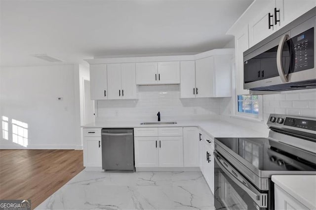 kitchen featuring white cabinetry, appliances with stainless steel finishes, sink, and backsplash