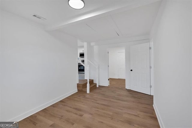 unfurnished room featuring beamed ceiling and hardwood / wood-style floors