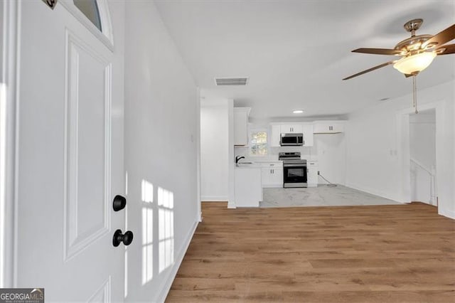 interior space featuring ceiling fan, sink, and light wood-type flooring