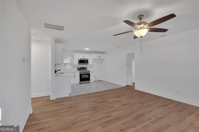 unfurnished living room featuring sink, light hardwood / wood-style floors, and ceiling fan