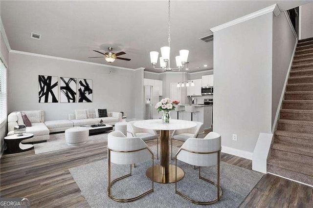 dining area featuring crown molding, ceiling fan with notable chandelier, and dark wood-type flooring