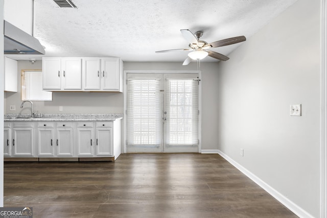 kitchen with white cabinetry, dark hardwood / wood-style floors, sink, and light stone counters