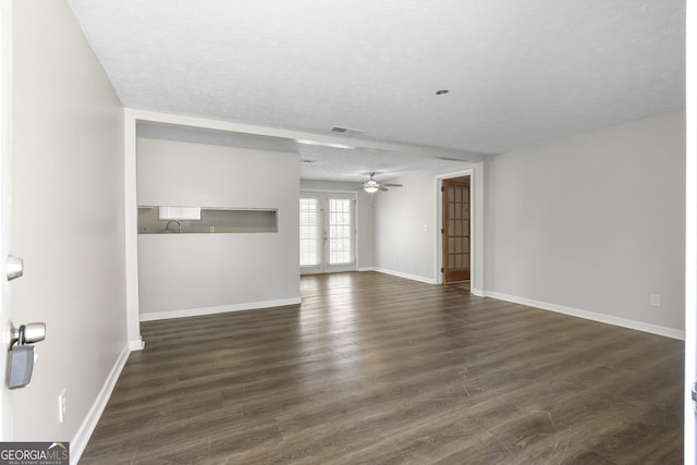 empty room featuring french doors, ceiling fan, dark hardwood / wood-style flooring, and a textured ceiling