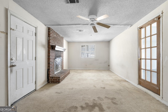 unfurnished living room with a brick fireplace, light colored carpet, a textured ceiling, and ceiling fan