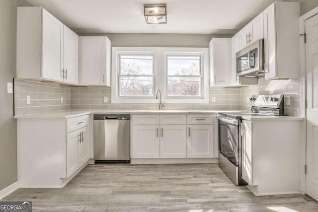 kitchen featuring sink, light hardwood / wood-style floors, white cabinets, and appliances with stainless steel finishes