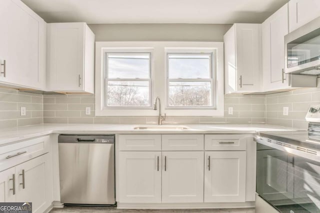 kitchen with sink, backsplash, stainless steel appliances, and white cabinets