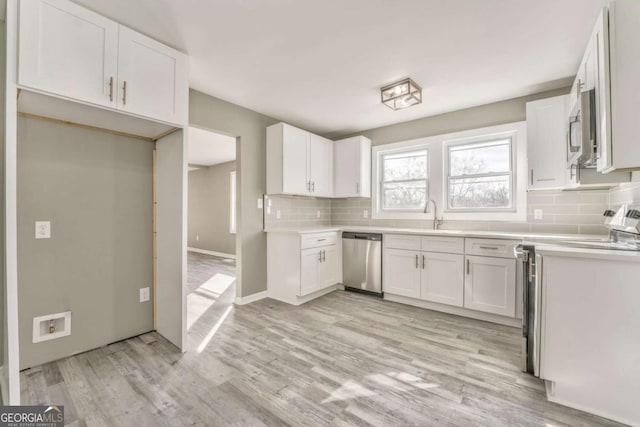 kitchen featuring white cabinetry, decorative backsplash, light hardwood / wood-style flooring, and appliances with stainless steel finishes