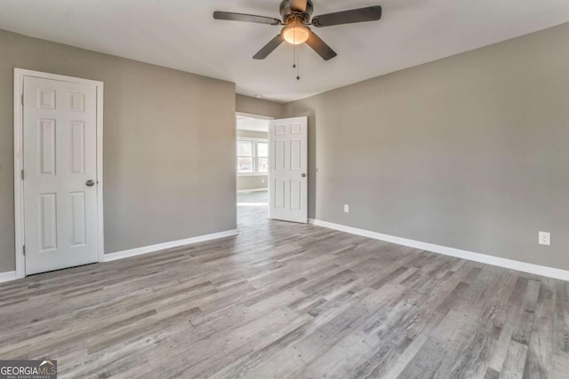 empty room with ceiling fan and light hardwood / wood-style flooring