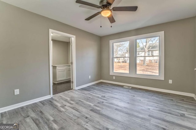 unfurnished bedroom featuring ceiling fan, ensuite bathroom, and light hardwood / wood-style flooring