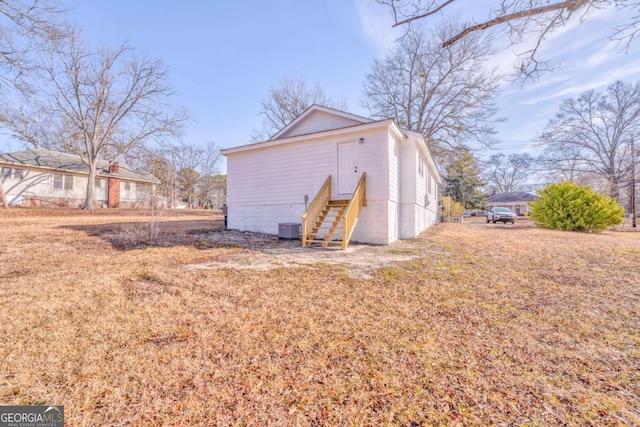 view of property exterior featuring central AC unit and a lawn