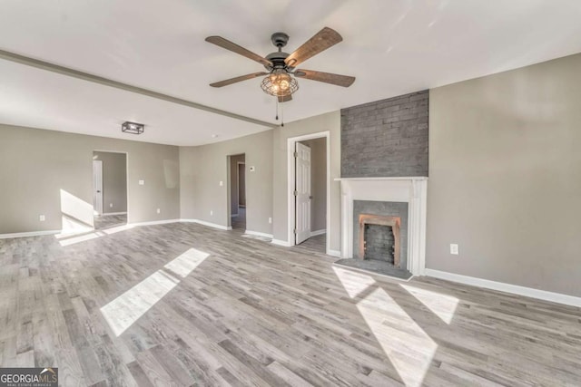 unfurnished living room featuring ceiling fan, a fireplace, and light hardwood / wood-style flooring