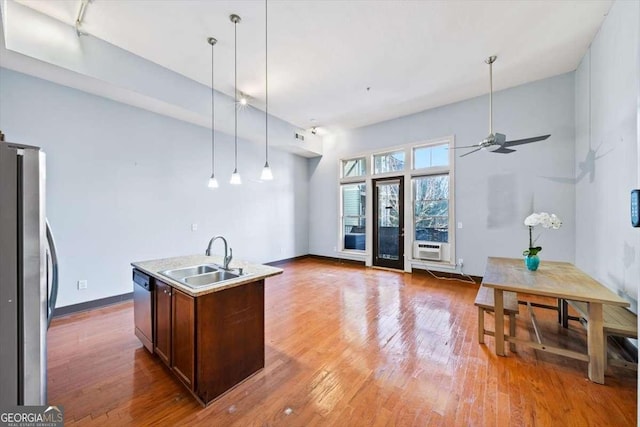 kitchen featuring sink, wood-type flooring, decorative light fixtures, a center island with sink, and appliances with stainless steel finishes