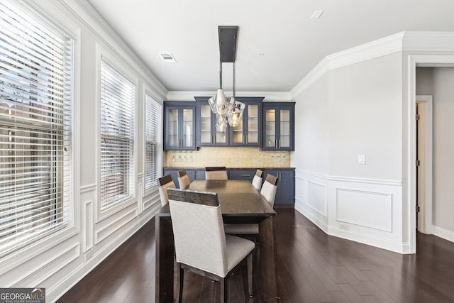 dining space with dark wood-type flooring, crown molding, and a notable chandelier