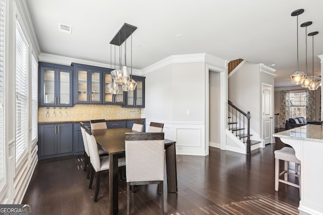 dining area featuring crown molding, a notable chandelier, and dark hardwood / wood-style flooring