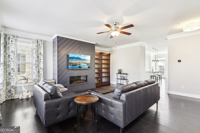 living room featuring dark hardwood / wood-style flooring, crown molding, a large fireplace, and ceiling fan