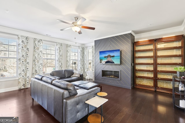 living room with dark wood-type flooring, ceiling fan, ornamental molding, and a fireplace