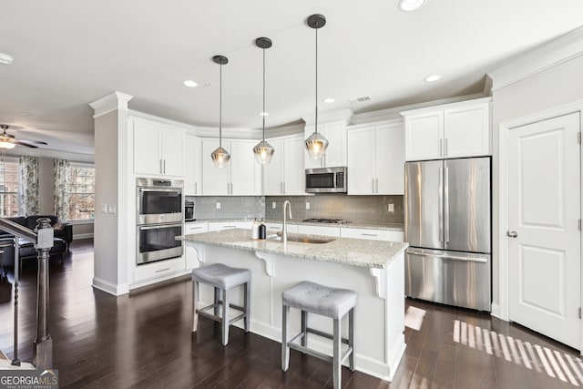 kitchen with a kitchen island with sink, sink, pendant lighting, and stainless steel appliances