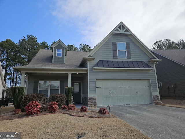 view of front of property with covered porch, a garage, driveway, stone siding, and a standing seam roof