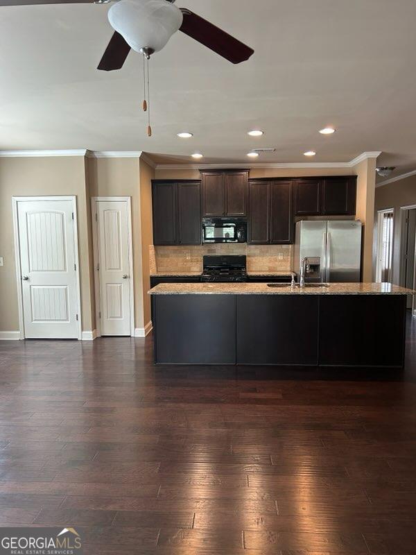 kitchen with black appliances, dark wood finished floors, a sink, and dark brown cabinetry