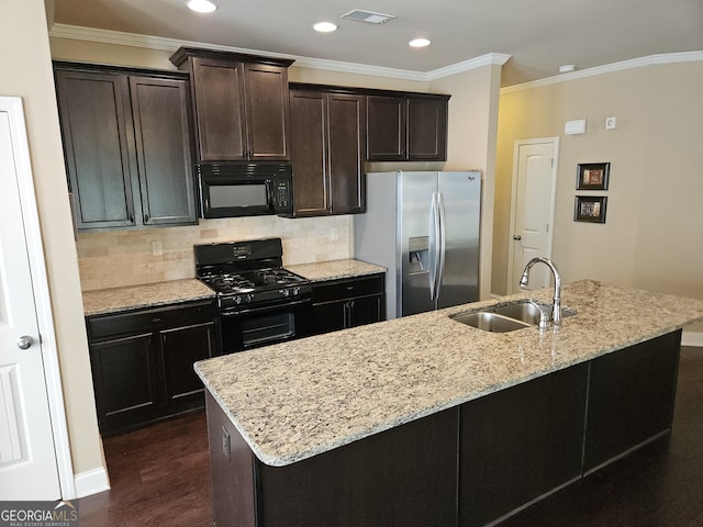 kitchen with light stone counters, dark wood-type flooring, a sink, black appliances, and a center island with sink