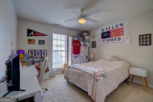 carpeted bedroom with ceiling fan and a textured ceiling