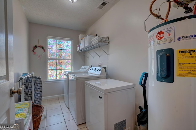 laundry area with water heater, washing machine and dryer, light tile patterned floors, and a textured ceiling