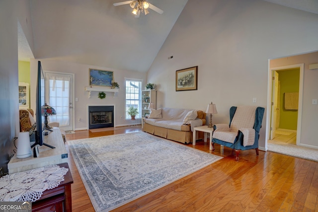 living room with ceiling fan, wood-type flooring, and high vaulted ceiling