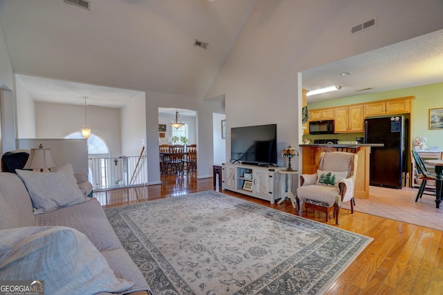 living room with high vaulted ceiling and light hardwood / wood-style flooring