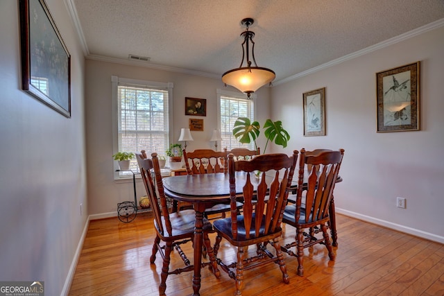 dining room with crown molding, light hardwood / wood-style floors, and a textured ceiling