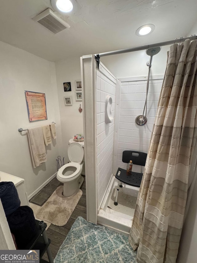 bathroom featuring wood-type flooring, toilet, and a shower with curtain